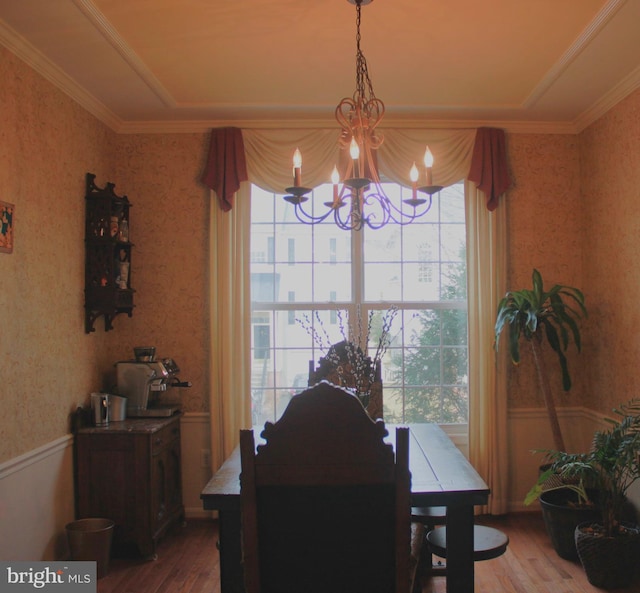 dining space featuring a chandelier, a wainscoted wall, wallpapered walls, and wood finished floors