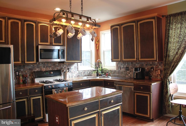 kitchen with a kitchen island, tasteful backsplash, appliances with stainless steel finishes, and a sink