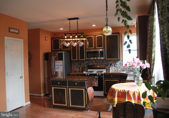 kitchen with decorative backsplash, dark brown cabinetry, a center island, and stainless steel appliances