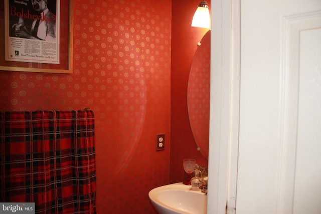 bathroom with wallpapered walls and a sink