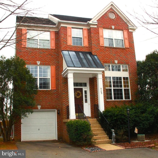 view of front of home with a garage, brick siding, driveway, and a standing seam roof