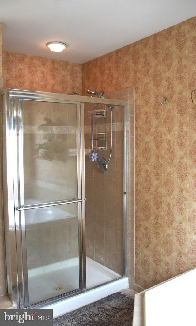 bathroom with a shower stall and wallpapered walls