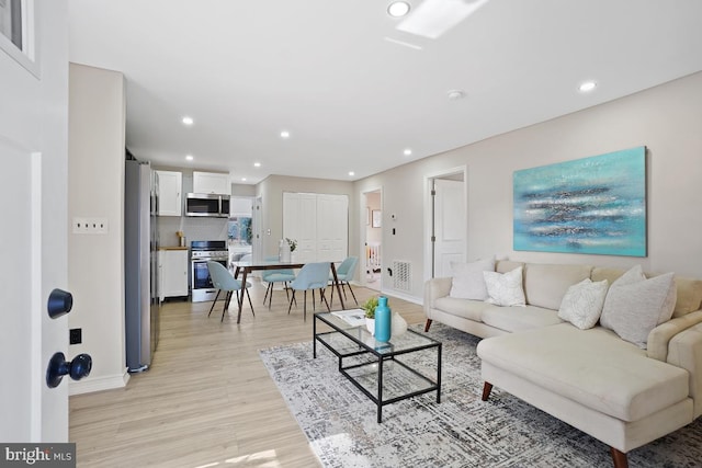 living room featuring recessed lighting, visible vents, light wood-style flooring, and baseboards