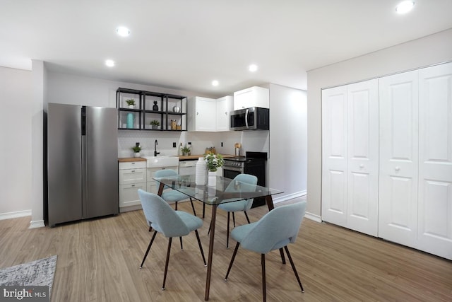 kitchen featuring light wood-style flooring, appliances with stainless steel finishes, white cabinets, and a sink