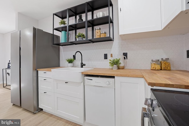 kitchen featuring butcher block counters, appliances with stainless steel finishes, white cabinets, and a sink