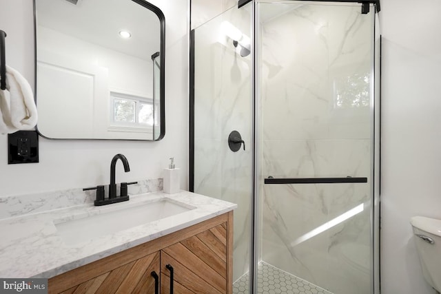 bathroom featuring toilet, vanity, and a marble finish shower