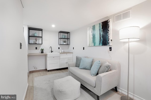 living room with recessed lighting, visible vents, baseboards, light wood finished floors, and indoor wet bar