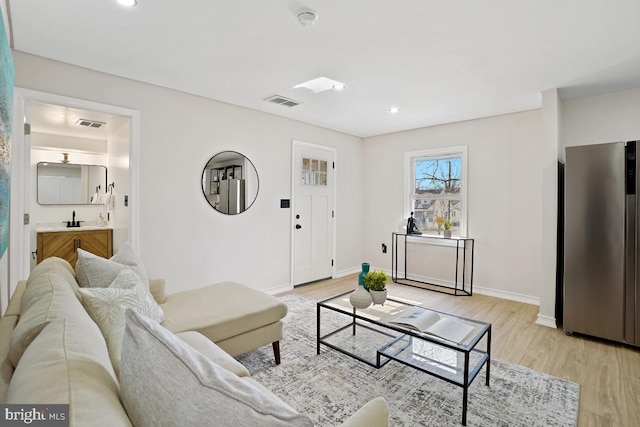 living room featuring baseboards, recessed lighting, visible vents, and light wood-style floors