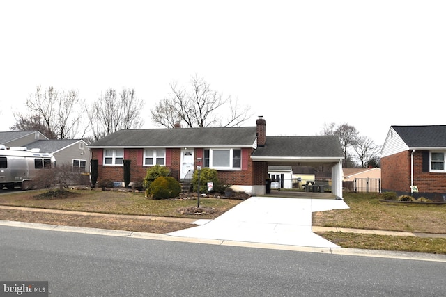 ranch-style home with concrete driveway, a chimney, an attached carport, a front lawn, and brick siding