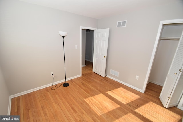 unfurnished bedroom with a closet, light wood-type flooring, visible vents, and baseboards