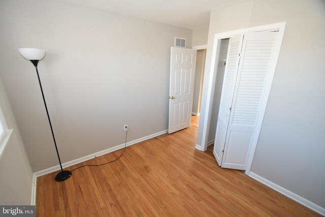 unfurnished bedroom with light wood-style flooring, a closet, visible vents, and baseboards