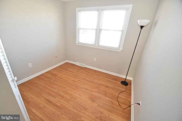 unfurnished room featuring light wood-style floors, visible vents, and baseboards