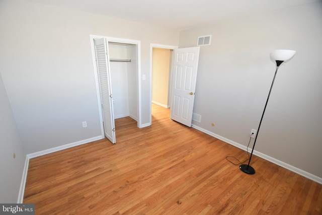 unfurnished bedroom featuring light wood finished floors, baseboards, visible vents, and a closet