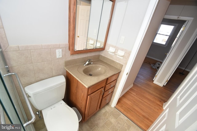 bathroom featuring toilet, wood finished floors, vanity, and tile walls