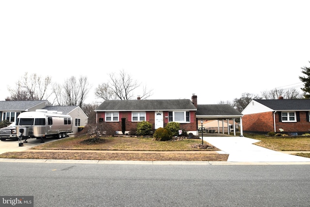 single story home featuring driveway, brick siding, a chimney, and a residential view