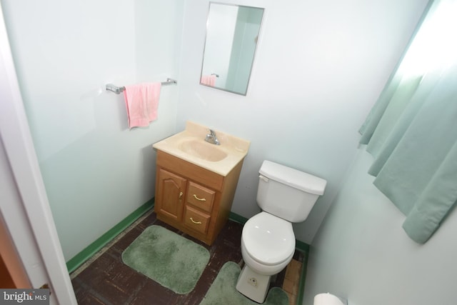 bathroom featuring baseboards, vanity, and toilet