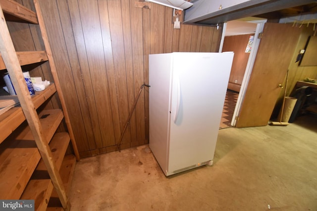 finished basement featuring wood walls and freestanding refrigerator