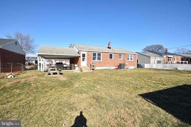 rear view of house featuring a yard, brick siding, cooling unit, and fence