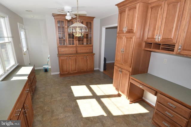 interior space featuring plenty of natural light, built in desk, baseboards, and an inviting chandelier