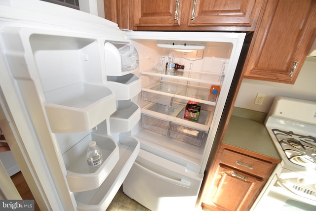 room details with light countertops, refrigerator, white range with gas stovetop, and brown cabinets