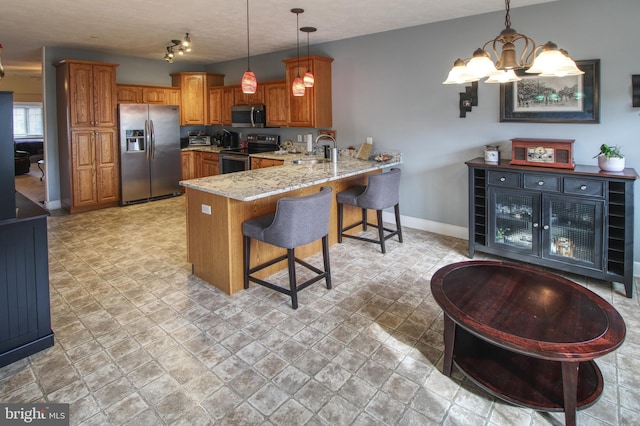 kitchen with baseboards, brown cabinetry, a peninsula, light stone countertops, and stainless steel appliances