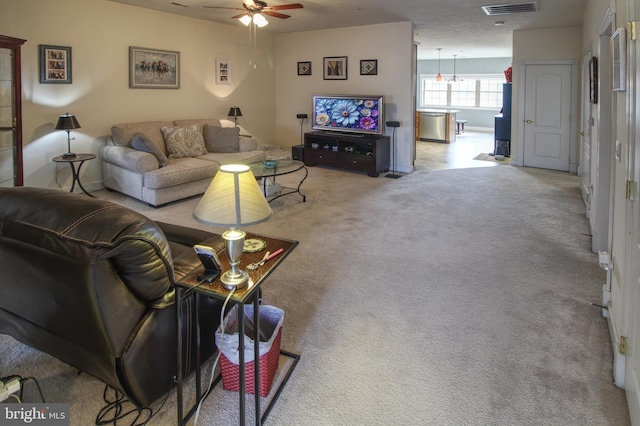 living room featuring carpet, visible vents, and ceiling fan