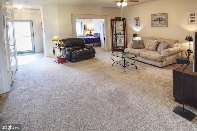 carpeted living area with a ceiling fan