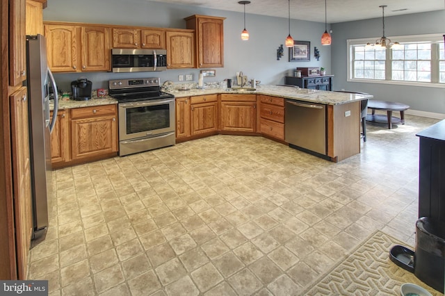 kitchen featuring a peninsula, appliances with stainless steel finishes, brown cabinetry, and a sink