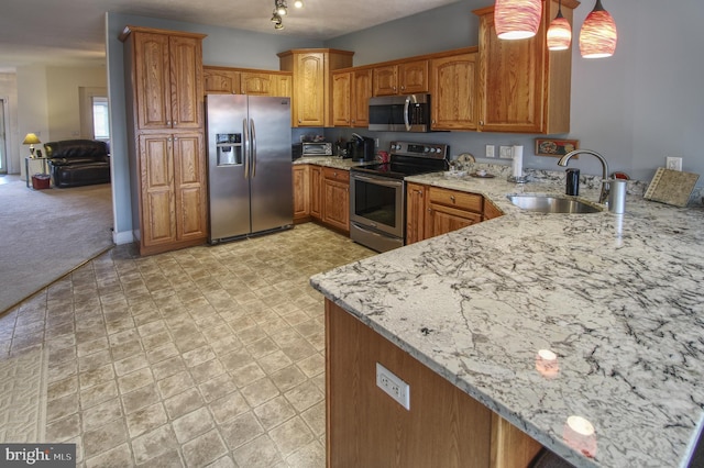 kitchen with light stone counters, brown cabinets, appliances with stainless steel finishes, a sink, and a peninsula