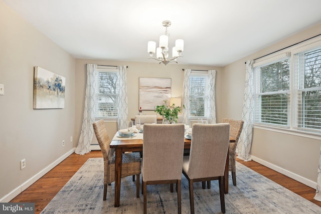 dining space featuring a healthy amount of sunlight, a notable chandelier, baseboards, and wood finished floors