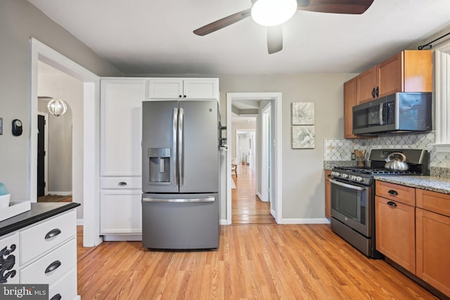 kitchen featuring appliances with stainless steel finishes, light wood-type flooring, brown cabinets, and tasteful backsplash