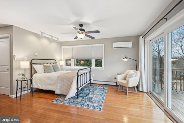 bedroom featuring a wall unit AC, wood-type flooring, access to outside, and a baseboard radiator