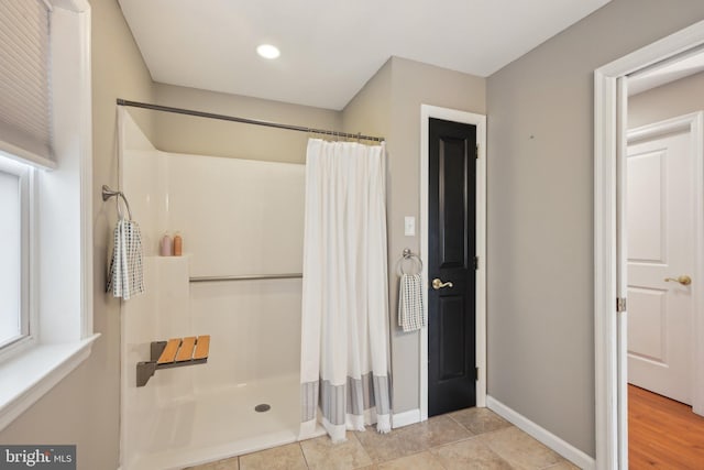 full bath with curtained shower, tile patterned floors, and baseboards