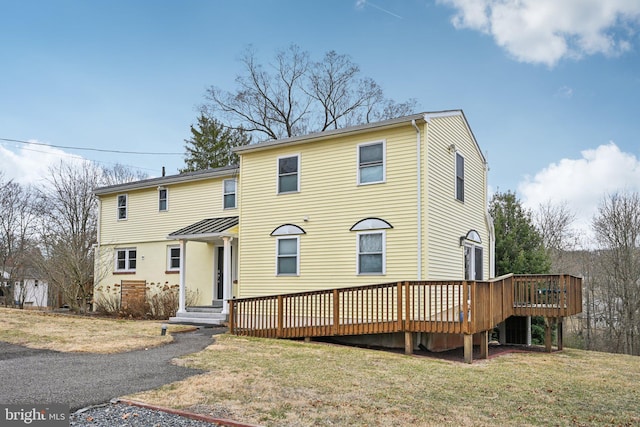 view of front of property featuring a front lawn, a standing seam roof, and a wooden deck