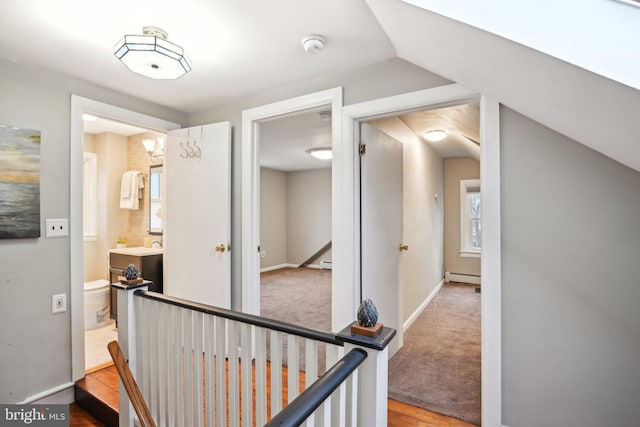 hall featuring an upstairs landing, carpet, baseboards, and baseboard heating