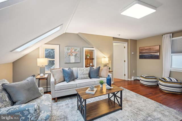 living room featuring vaulted ceiling with skylight, a baseboard heating unit, and wood finished floors