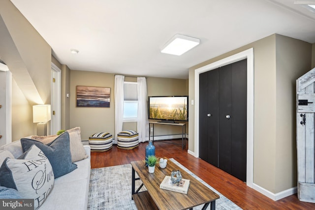 living area featuring baseboards, baseboard heating, and wood finished floors