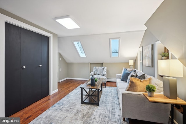 interior space featuring vaulted ceiling with skylight, baseboards, baseboard heating, and wood finished floors