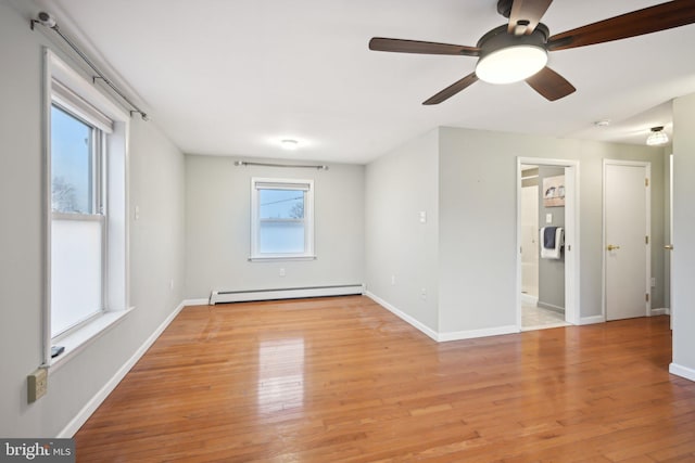 spare room with a baseboard radiator, light wood-style flooring, and baseboards