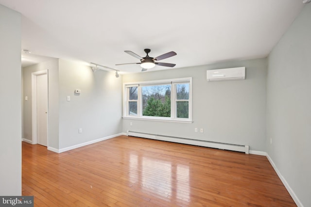 spare room featuring a baseboard heating unit, a ceiling fan, baseboards, an AC wall unit, and hardwood / wood-style floors