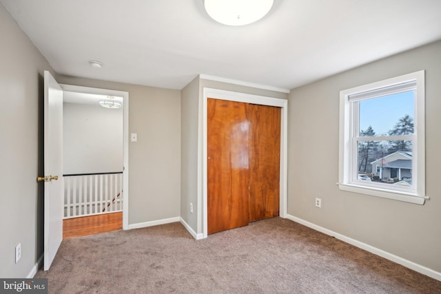 unfurnished bedroom with carpet floors, a closet, and baseboards