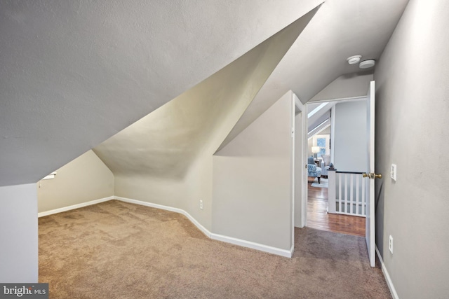 additional living space featuring carpet floors, baseboards, a textured ceiling, and lofted ceiling