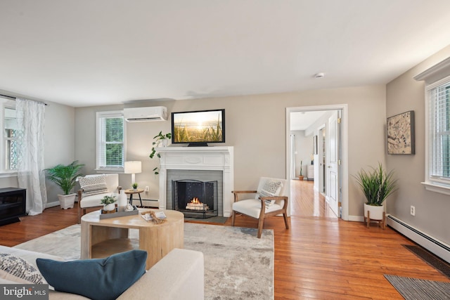 living room with a wall unit AC, hardwood / wood-style flooring, a baseboard radiator, a fireplace, and a baseboard heating unit