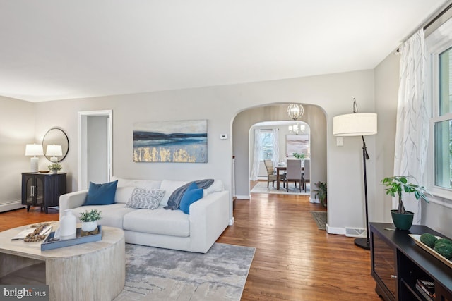 living area with baseboards, arched walkways, and wood finished floors