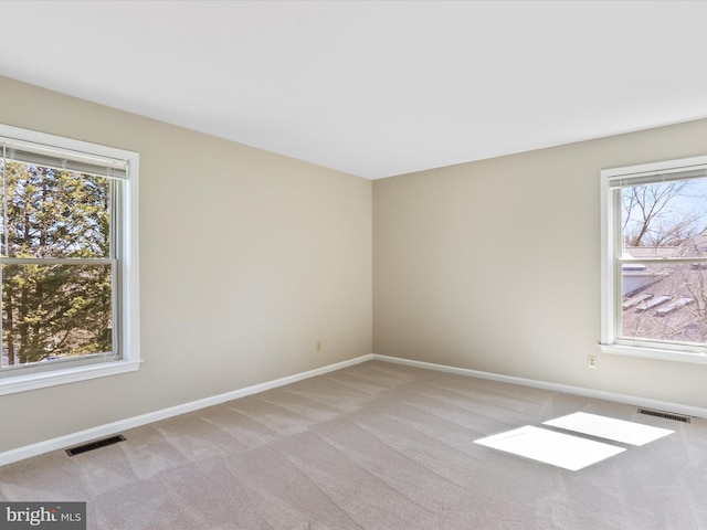 spare room featuring light carpet, healthy amount of natural light, and baseboards