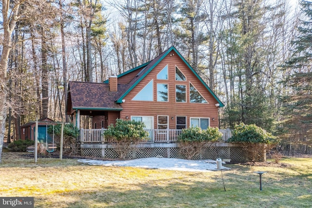 view of front of house with a chimney, a front lawn, and roof with shingles