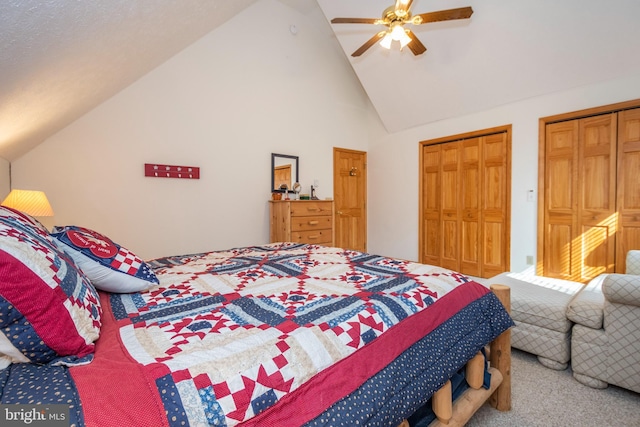 carpeted bedroom featuring high vaulted ceiling, two closets, and a ceiling fan