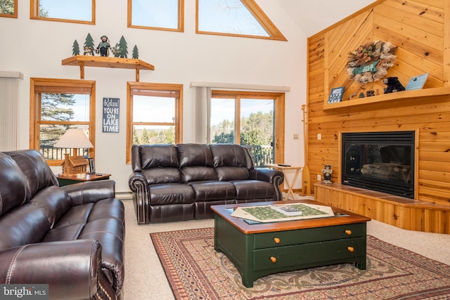 carpeted living area featuring high vaulted ceiling and a glass covered fireplace