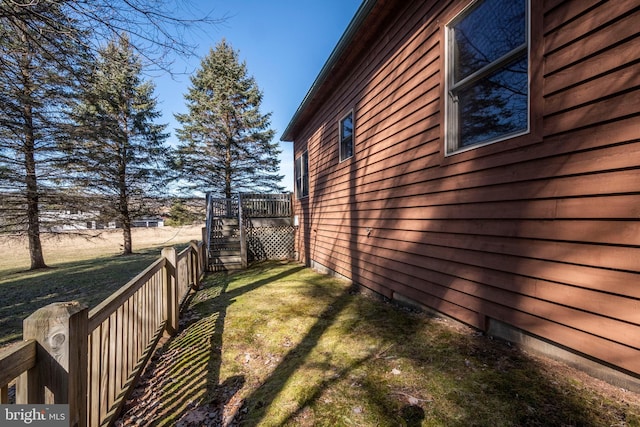 view of side of property with a yard, stairway, and fence