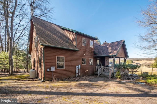 exterior space featuring a shingled roof and a chimney